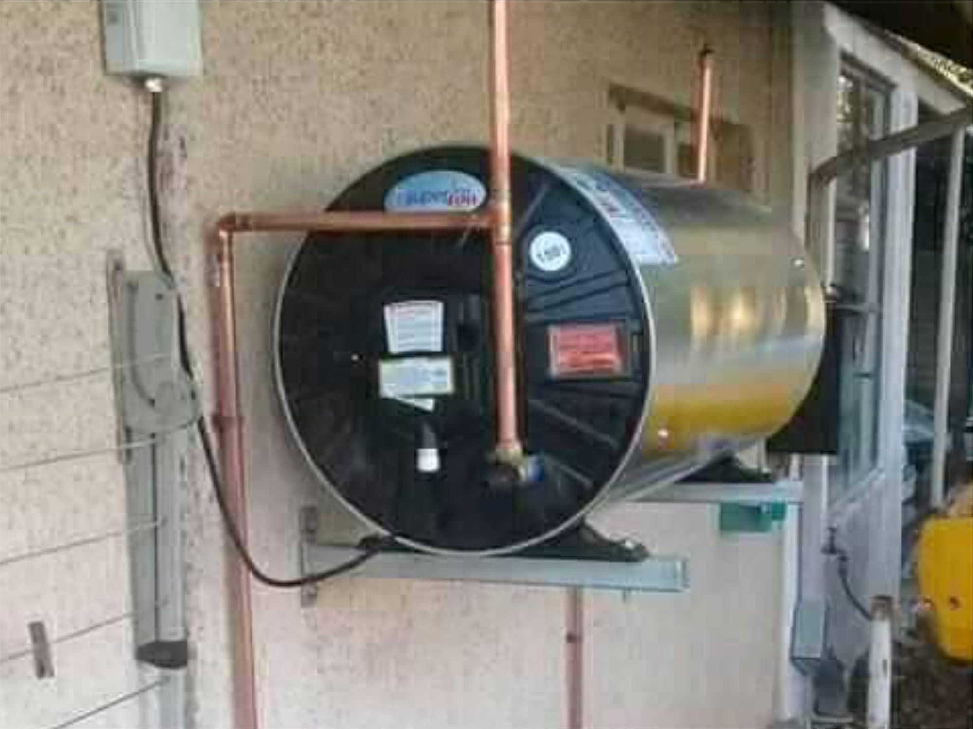 Horizontal geyser mounted on an outside wall with copper pipework