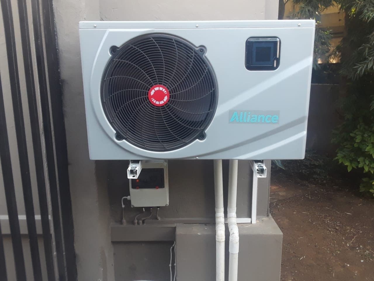 Pool heat pump mounted on a wall with its control box