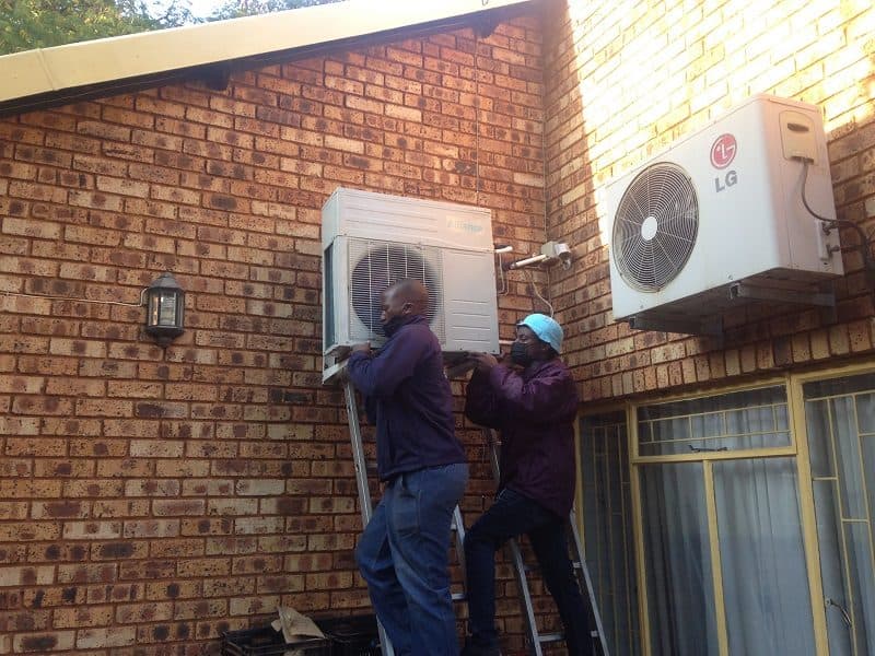 Panwell technicians installing an outdoor unit on a brick wall